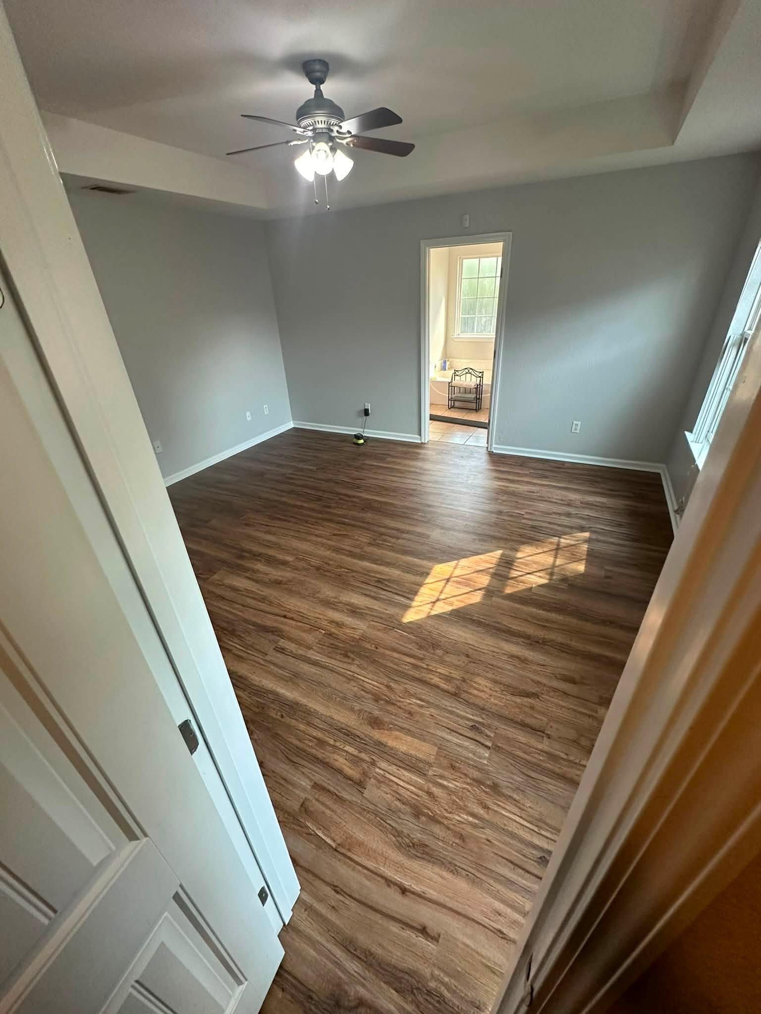 Finished bedroom with new wood-look plank flooring and white baseboards