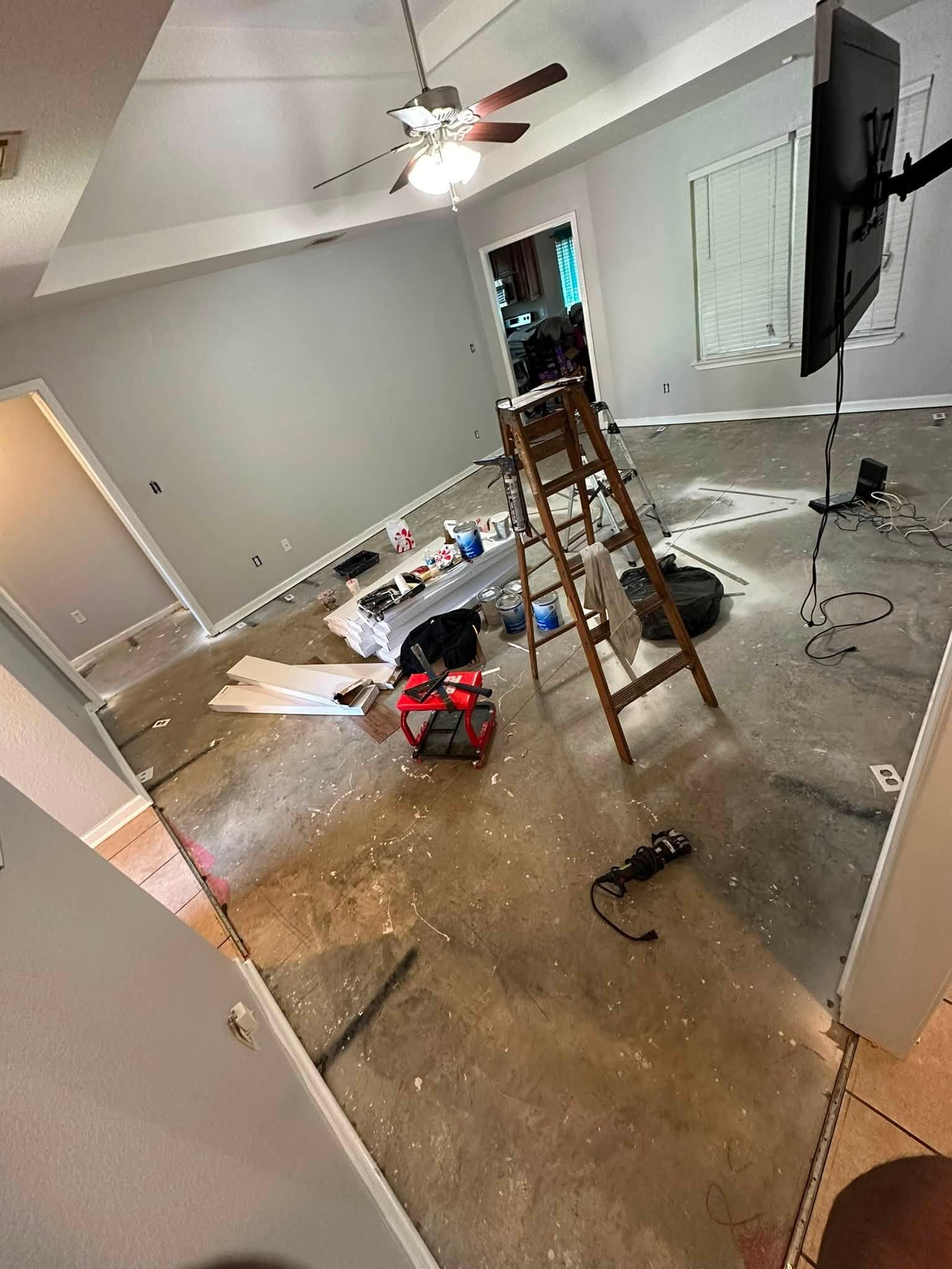 Main room stripped to the concrete slab mid-job, with new baseboards and tools on site